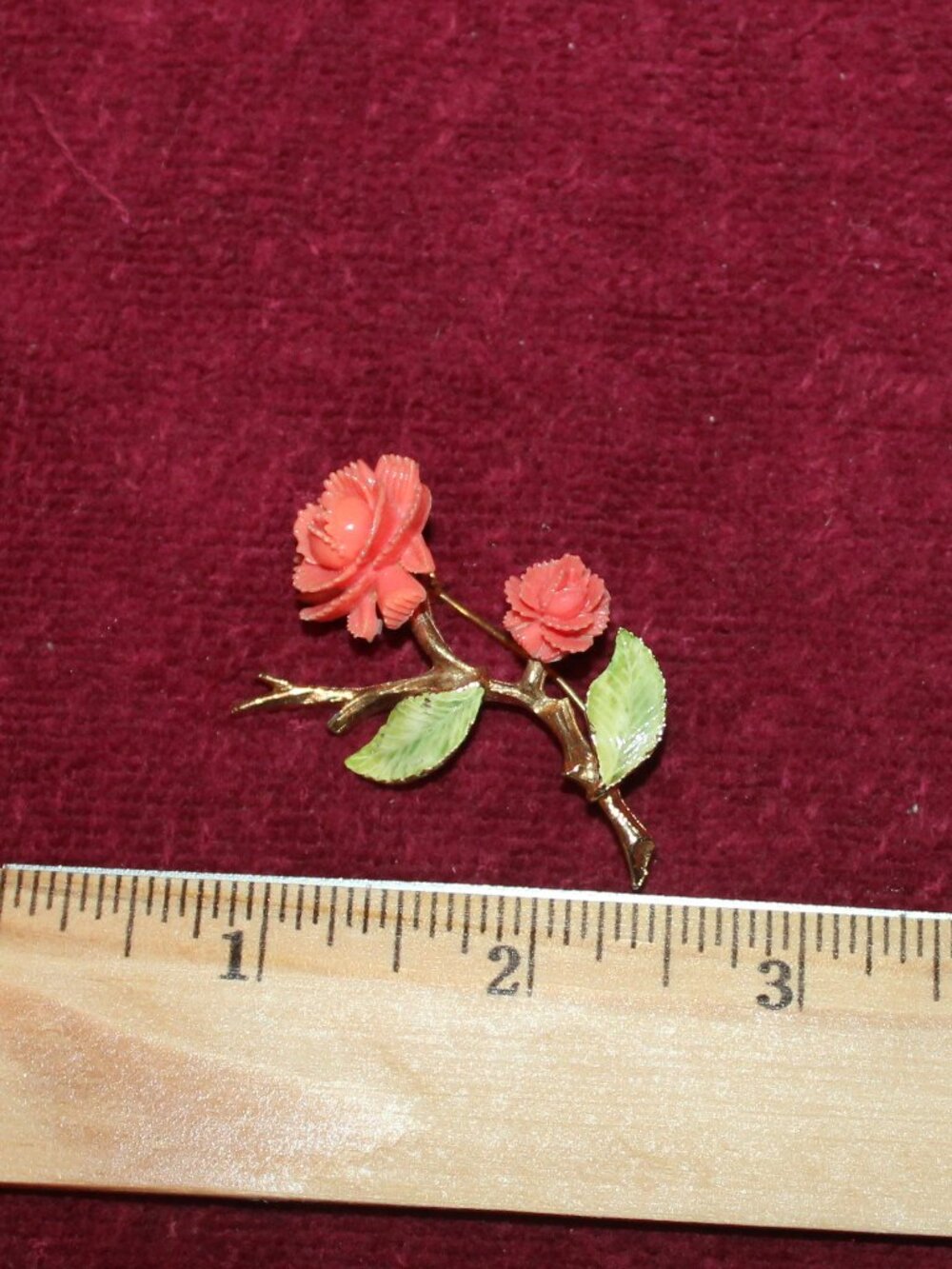 Vintage coral-colored plastic rose brooch with green enamel leaves